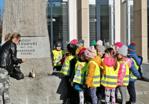 Dzieci zapalają znicz pod pomnikiem Marszałka Polski